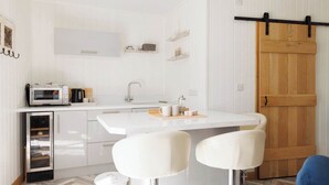 A compact kitchen with a microwave, sink, and bar stools.
