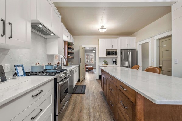 A modern kitchen with white cabinets, stainless steel appliances, and a wooden countertop.
