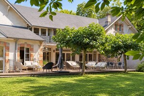 A hotel with outdoor seating, a covered patio, and a well-maintained lawn. - Luxurious residence for 30 people, with a pool and a large garden (Garrevaques)