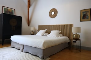 A neatly made bed with a headboard, two bedside lamps, a round mirror, and a framed picture on the wall. - Prestigious residence for 30 people, swimming pool - large garden (Garrevaques)