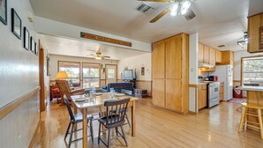 Un'ampia cucina con mobili in legno, una zona pranzo con tavolo e sedie, e una ventola a soffitto.