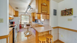 Una cucina con mobili in legno, un frigorifero, un forno a microonde e un lavandino. È presente una bancone con sgabelli e un calendario appeso al muro.