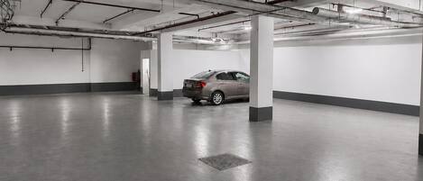 Ett parkeringsgarage med betonggolv, stålbalkar och pelare.