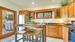 Una cocina moderna con armarios de madera, un refrigerador de acero inoxidable y un ventanal amplio.