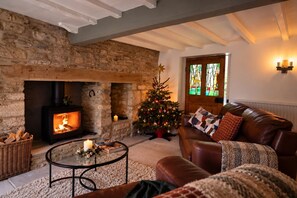 Un salon chaleureux avec une cheminée en pierre, un sapin de Noël, un canapé en cuir et une table à manger.