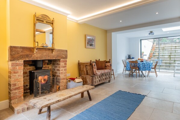 Una sala de estar acogedora con chimenea de ladrillo, un banco de madera y una zona de comedor con mesa y sillas.
