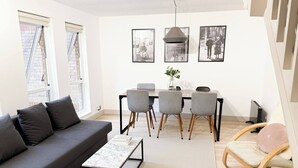 A modern living room with a grey sofa, a coffee table, a dining table with chairs, and framed pictures on the wall. - Entire 2 Bedroom House 7m To Station (Barnet)