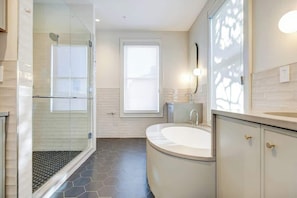 A modern bathroom with a glass shower enclosure, a freestanding bathtub, and a large mirror. - Jefferson Guest House | Entirely Renovated (Charlottesville)