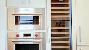 Une cuisine équipée de deux fours en acier inoxydable, d’un meuble en bois et d’une étagère avec des portes en verre.