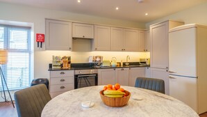 A modern kitchen with white cabinets, a marble countertop, and a dining area with a round table.