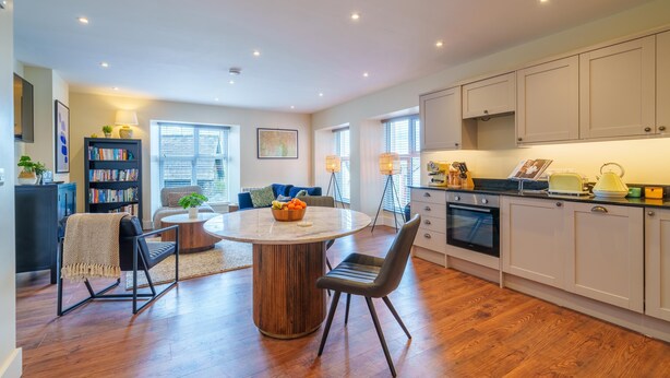 A modern kitchen with wooden cabinets, a round dining table, and a built-in oven.