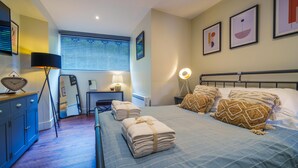 A hotel room with a bed, bedside lamps, a desk, and a window with blinds.