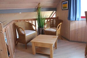 Una habitación de madera con dos sillas de mimbre y una pequeña mesa de madera.