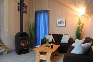 Una sala acogedora con una chimenea de leña, un conjunto de sofás, una mesita de centro y una cortina azul.
