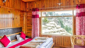 A wooden cabin room with a bed, a chair, and a window with curtains. - Mount View Dhanaulti Dreams (Dhanaulti)