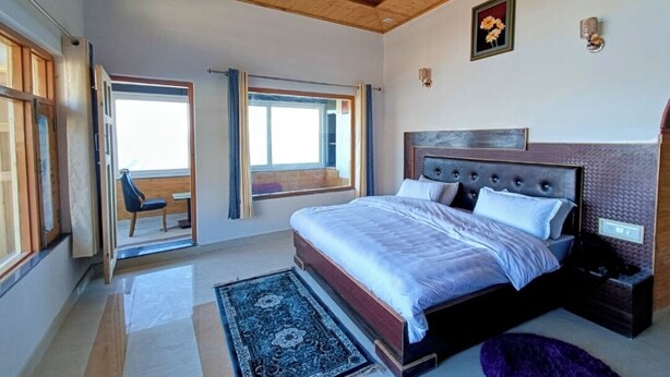 A bedroom with a large bed, a window, a wooden ceiling, and a nightstand. - Mount View Dhanaulti Dreams (Dhanaulti)