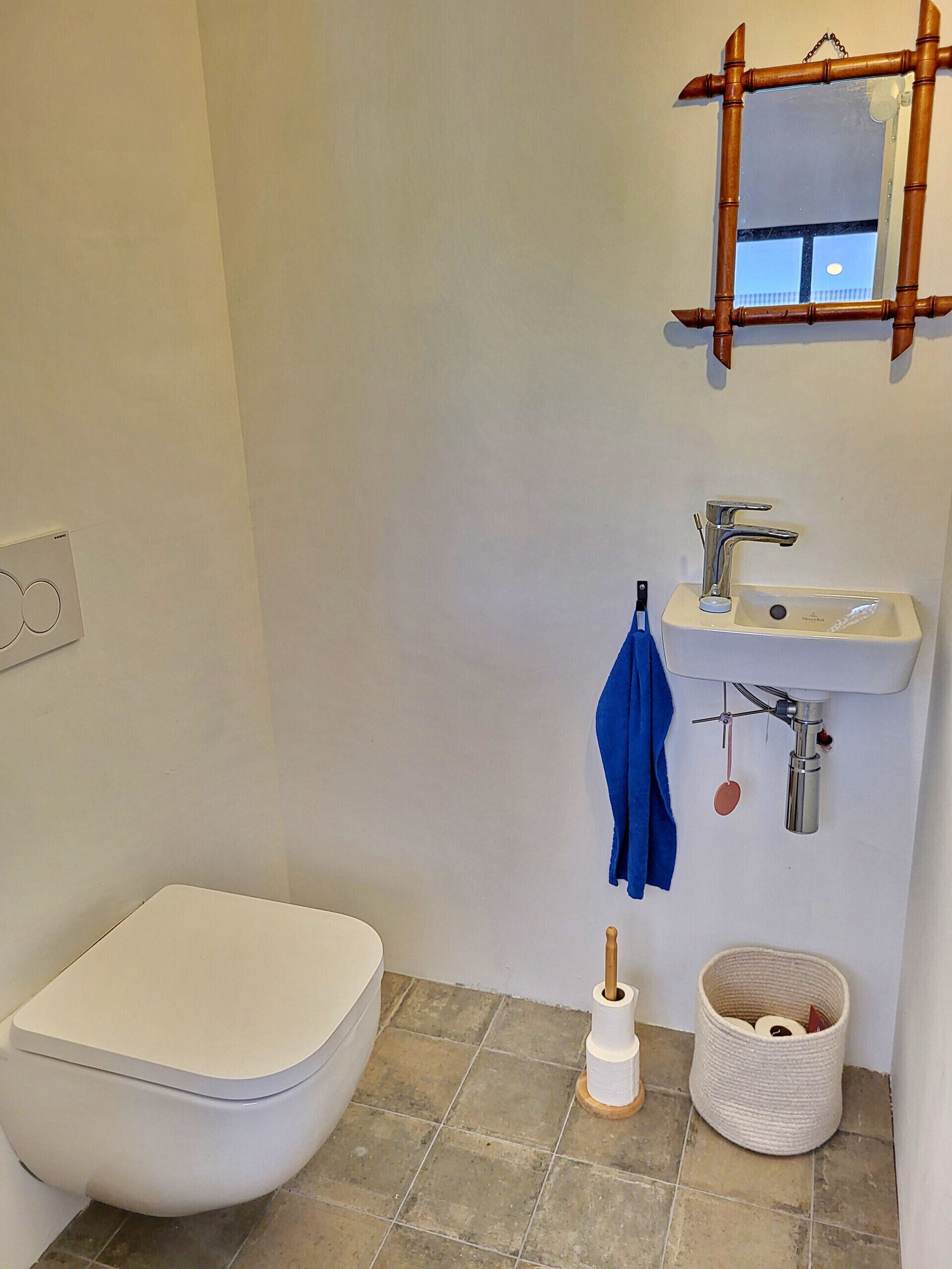A bathroom with a toilet, sink, and mirror.