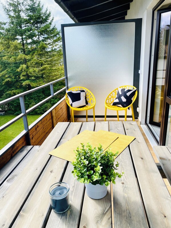 A balcony with two yellow chairs, a potted plant, and a candle.