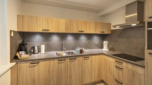 A modern kitchen with wooden cabinets, a stainless steel sink, and a built-in oven. - Holiday Home in North Holland Near Beach (Sint Maartensvlotbrug)