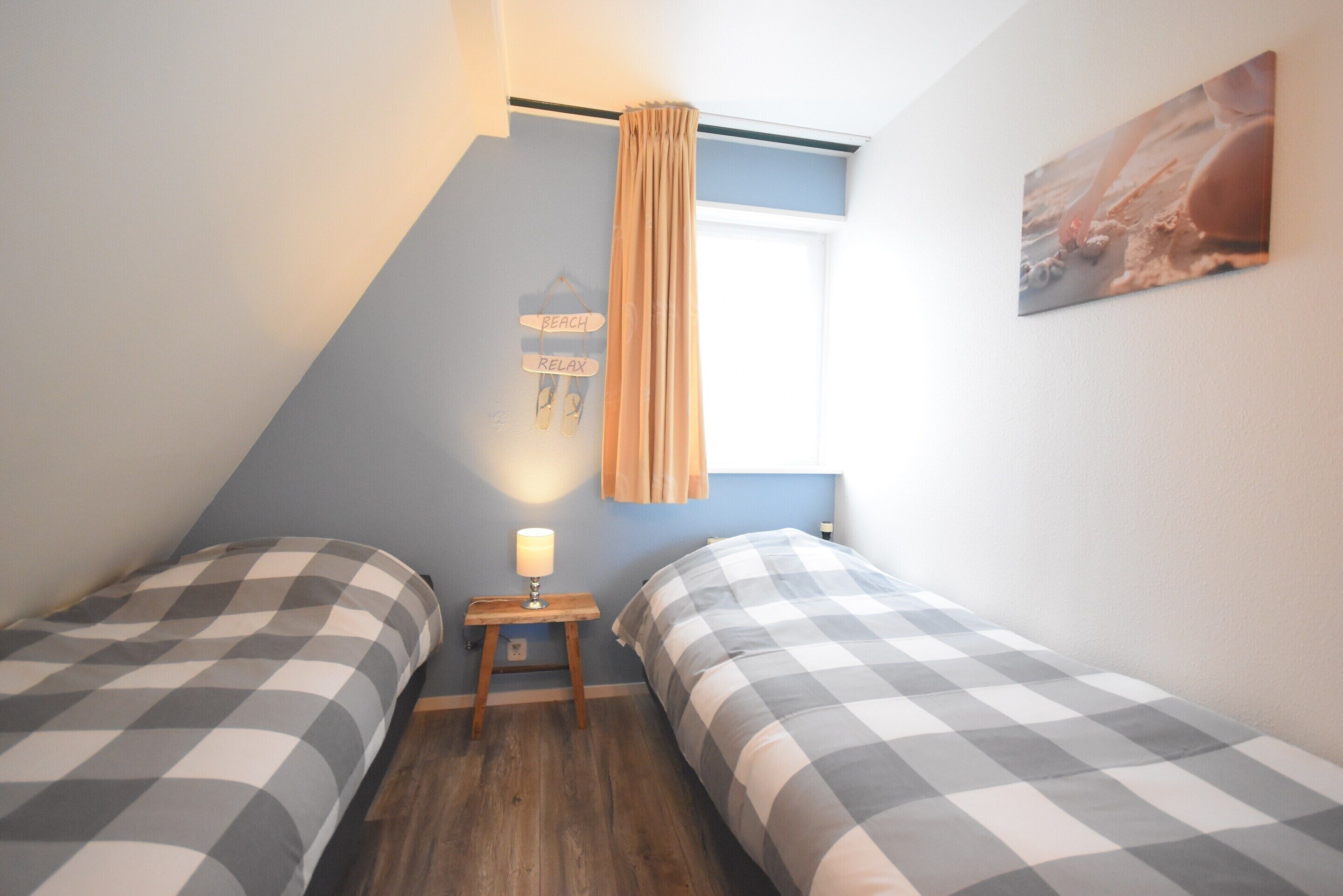 Ein Schlafzimmer mit zwei Betten, einem kleinen Nachttisch mit Lampe, einem hängenden Schild und einem Bild an der Wand.