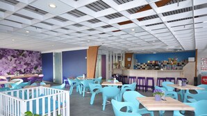 A modern restaurant with blue chairs and tables, a bar area, and a decorative wall with purple flowers. - Holiday Home in North Holland Near Beach (Sint Maartensvlotbrug)