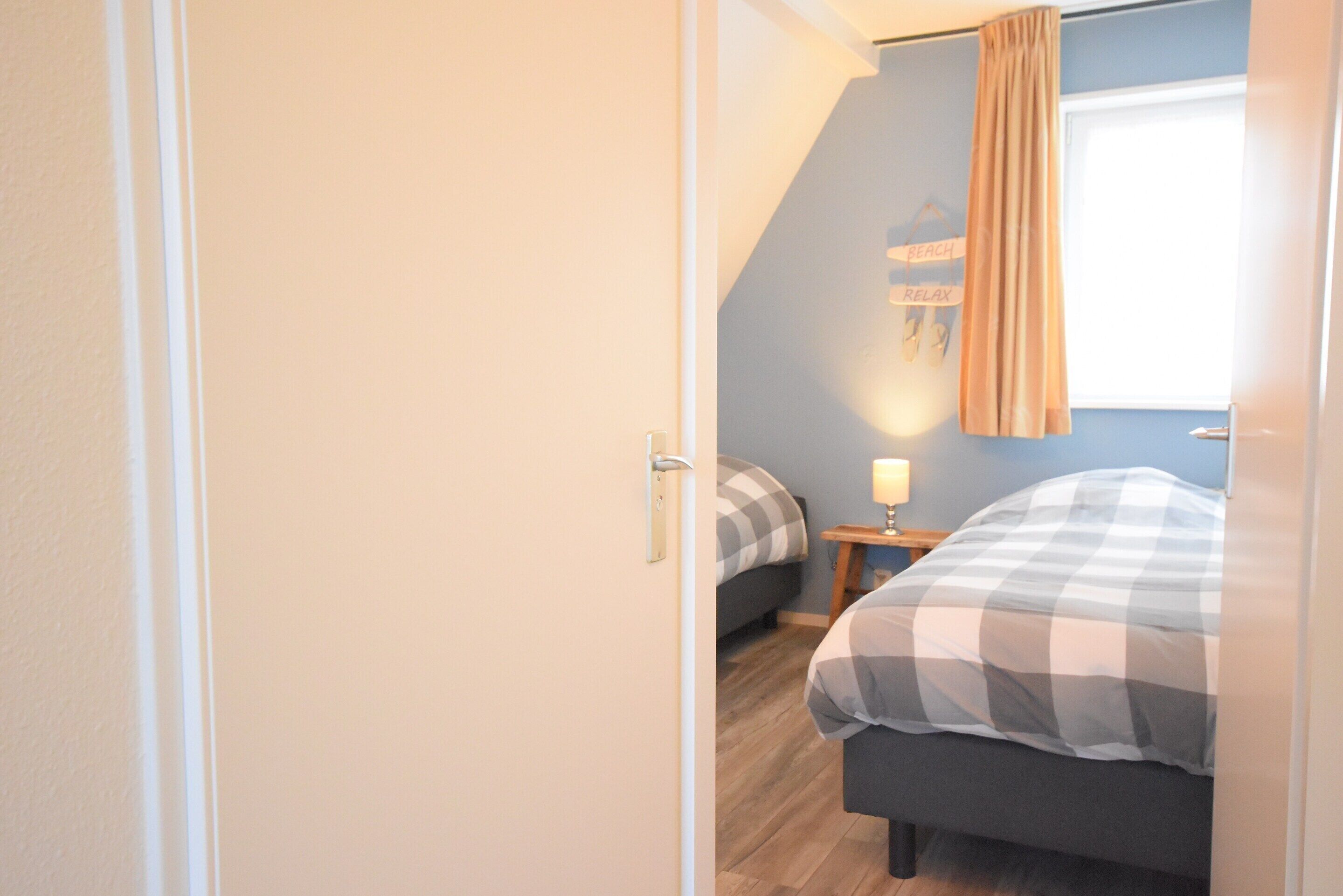 Une chambre à coucher comprenant un lit, une table de chevet et une étagère fixée au mur, sur laquelle se trouve une lampe.