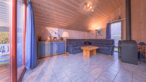 A cozy cabin interior with a wooden ceiling, a sofa, a small table, and a fireplace. - Ferienhaus im Ferienpark Mirow (Mirow)