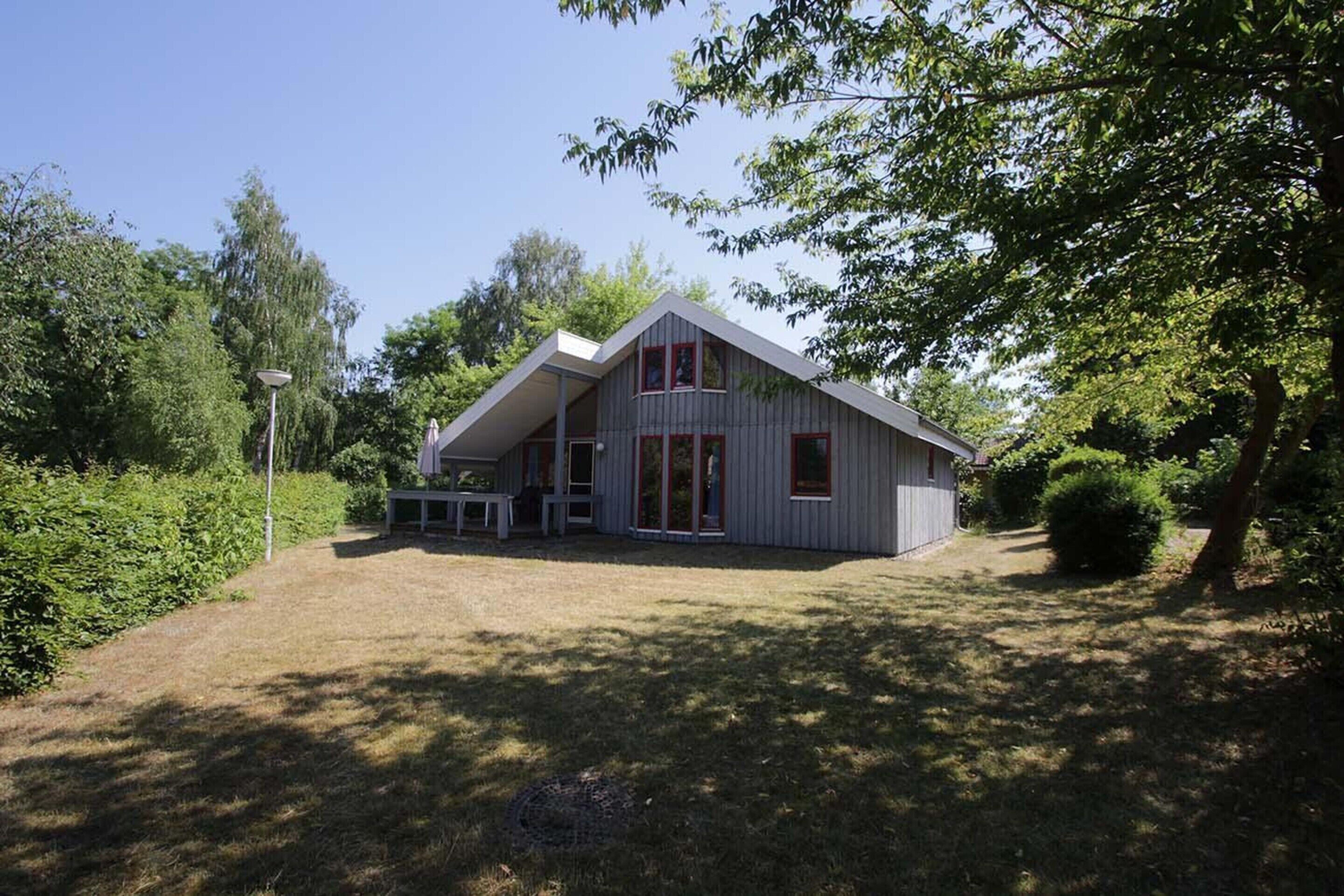 A modern house with a sloped roof, a porch with a bench, and a small garden area.