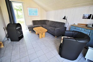 Ein Wohnzimmer mit einer Couch, einem Holztisch, einem schwarzen Ledersessel, einem schwarzen Kamin und einem blauen Schrank.