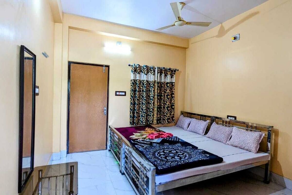A bedroom with a bed, curtains, a ceiling fan, and a door.