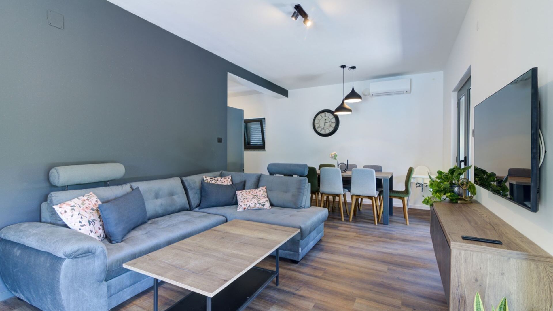Een moderne woonkamer met een hoekbank, een salontafel en een eetgedeelte met stoelen en een tafel.