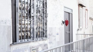 Een gebouw met een metalen balkonhek, een deur en een raam met decoratieve ijzeren spijlen.