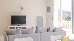 A modern living room with a grey sofa, a flat-screen TV, and a dining table with chairs. - Beautiful 6-person apartment - Arago District (Les Sables-d´Olonne)
