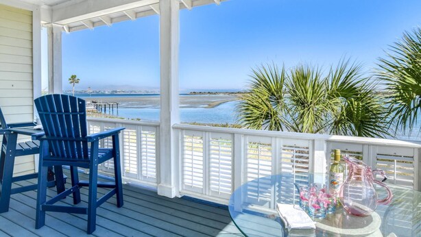 A covered outdoor area with a view of the ocean, featuring a glass table with drinks and a blue chair. - Waterfront! Incredible Views, Watch the Dolphins Play, Perfect for Groups, $300 in Free Tickets! (St. Augustine)