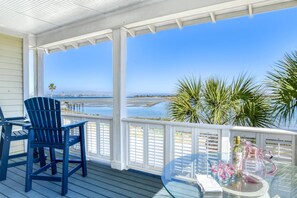 A covered outdoor area with a view of the ocean, featuring a glass table with drinks and a blue chair. - Waterfront! Incredible Views, Watch the Dolphins Play, Perfect for Groups, $300 in Free Tickets! (St. Augustine)
