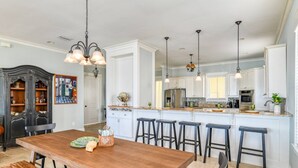 A spacious kitchen with a central island, bar stools, and a wooden dining table. - Waterfront! Incredible Views, Watch the Dolphins Play, Perfect for Groups, $300 in Free Tickets! (St. Augustine)