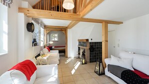 Un'ampia zona giorno con soffitto in legno a vista, un caminetto e un angolo salotto accogliente.