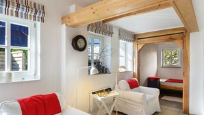 Una stanza accogliente con un divano bianco, un tavolino con una lampada e un letto con coperta rossa.