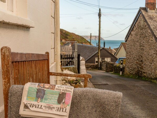 A newspaper on a chair outside a building with a stone wall and a wooden fence. - Beautiful private villa for 6 guests with WIFI, TV, patio and pets allowed (Portloe)