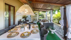 A covered outdoor dining area with wicker furniture, a white table set for a meal, and a hanging light fixture. - Wonderful private villa for 10 people with WIFI, hot tub, private pool, A/C and panoramic view (Terranuova Bracciolini)