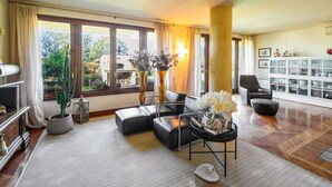 A spacious living room with a large window, a fireplace, and a dining area with a glass cabinet. - Wonderful private villa for 10 people with WIFI, hot tub, private pool, A/C and panoramic view (Terranuova Bracciolini)
