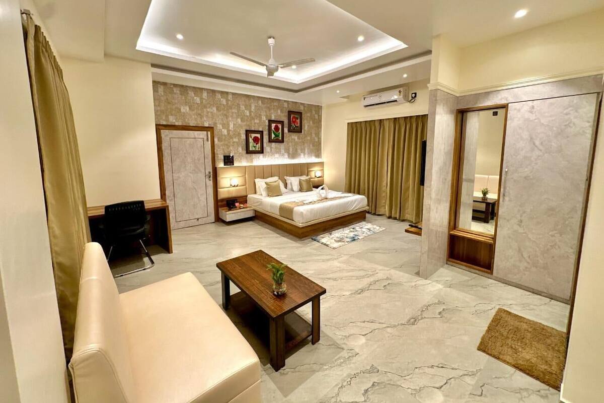 A modern hotel room with a bed, a sofa, a coffee table, and a desk.