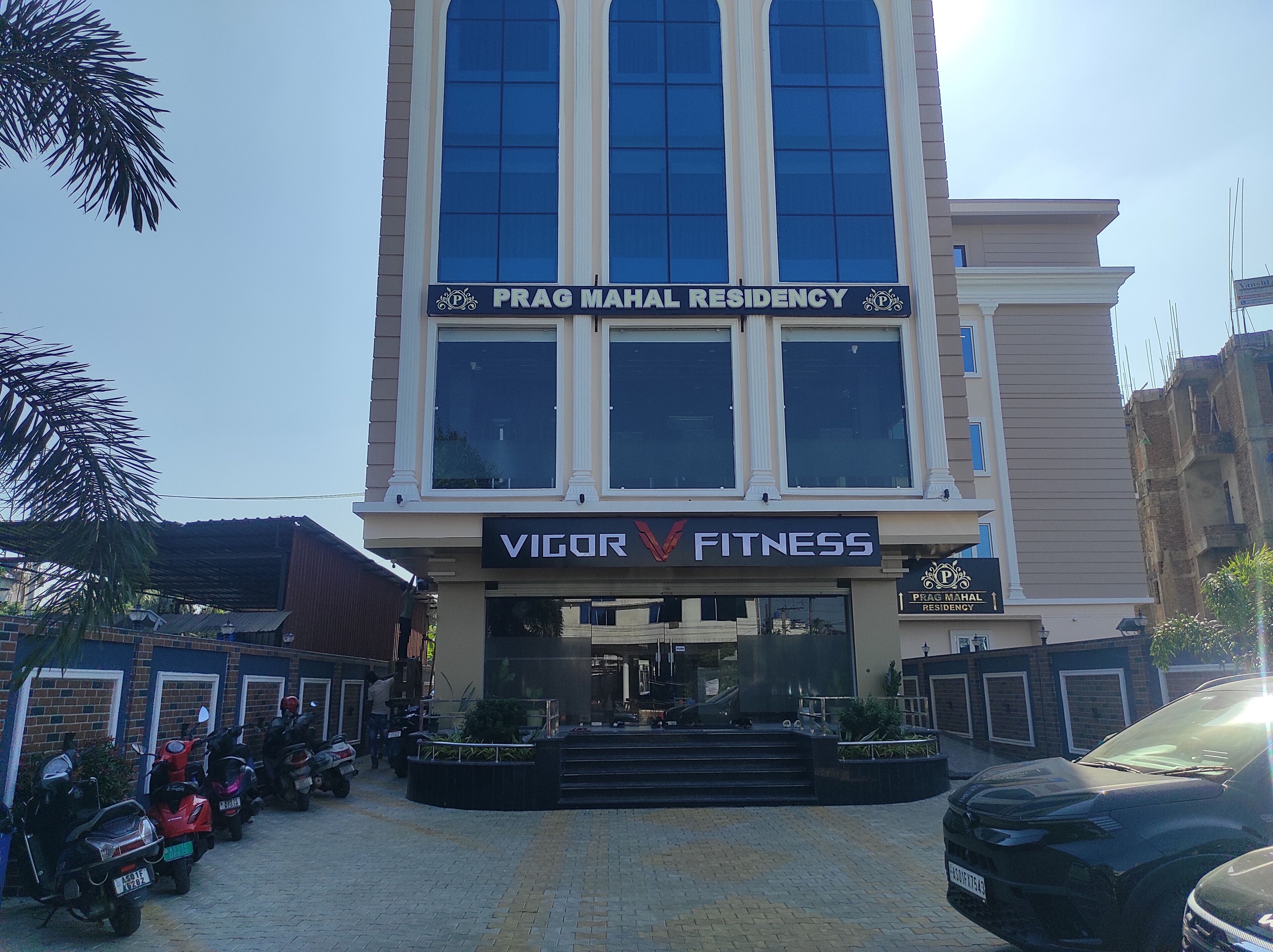 Un edificio con un cartel que indica 'Prag Mahal Residency' y 'Vigor Fitness'.