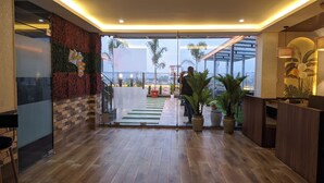 Un vestíbulo de hotel con suelo de madera, un mostrador de recepción y una puerta de cristal que da al exterior.