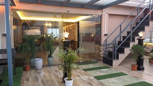 Un interior moderno con una escalera, plantas en macetas y una puerta de vidrio que da a una habitación.