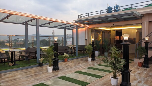 Una terraza en la azotea con paredes de vidrio, mobiliario exterior y plantas en macetas.