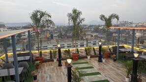 Une terrasse sur le toit, aménagée avec des espaces de détente en plein air, des plantes en pot et offrant une vue sur le paysage urbain.