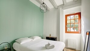 A bedroom with a bed, a bedside table, a lamp, a radiator, and a window. - Amboise Une Vie de château (Tours)