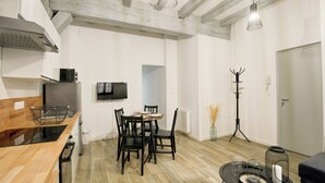 A modern kitchen with a dining area, wooden flooring, and a television mounted on the wall. - Amboise Une Vie de château (Tours)