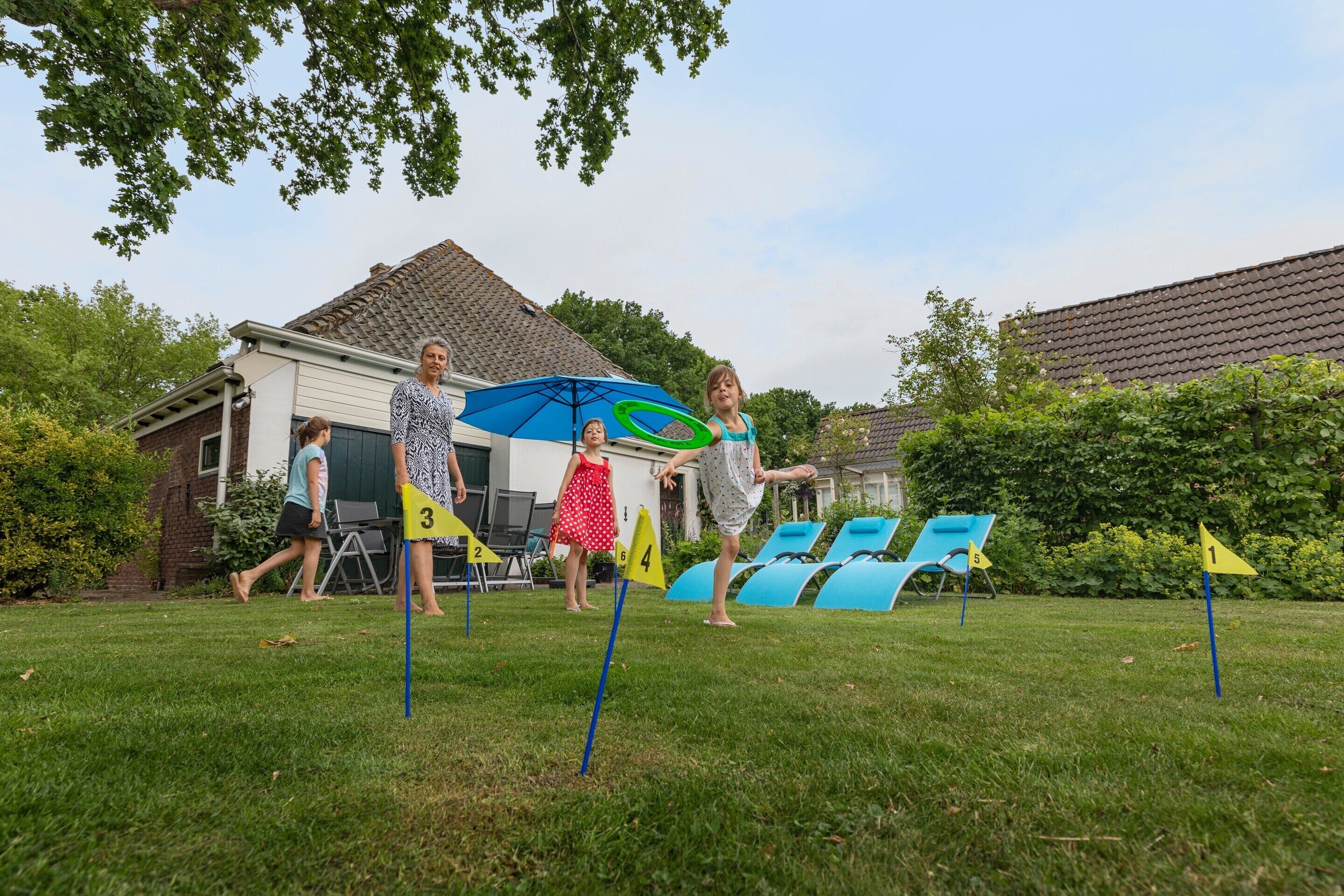 A grassy outdoor area with numbered flags, a blue umbrella, and a house in the background.